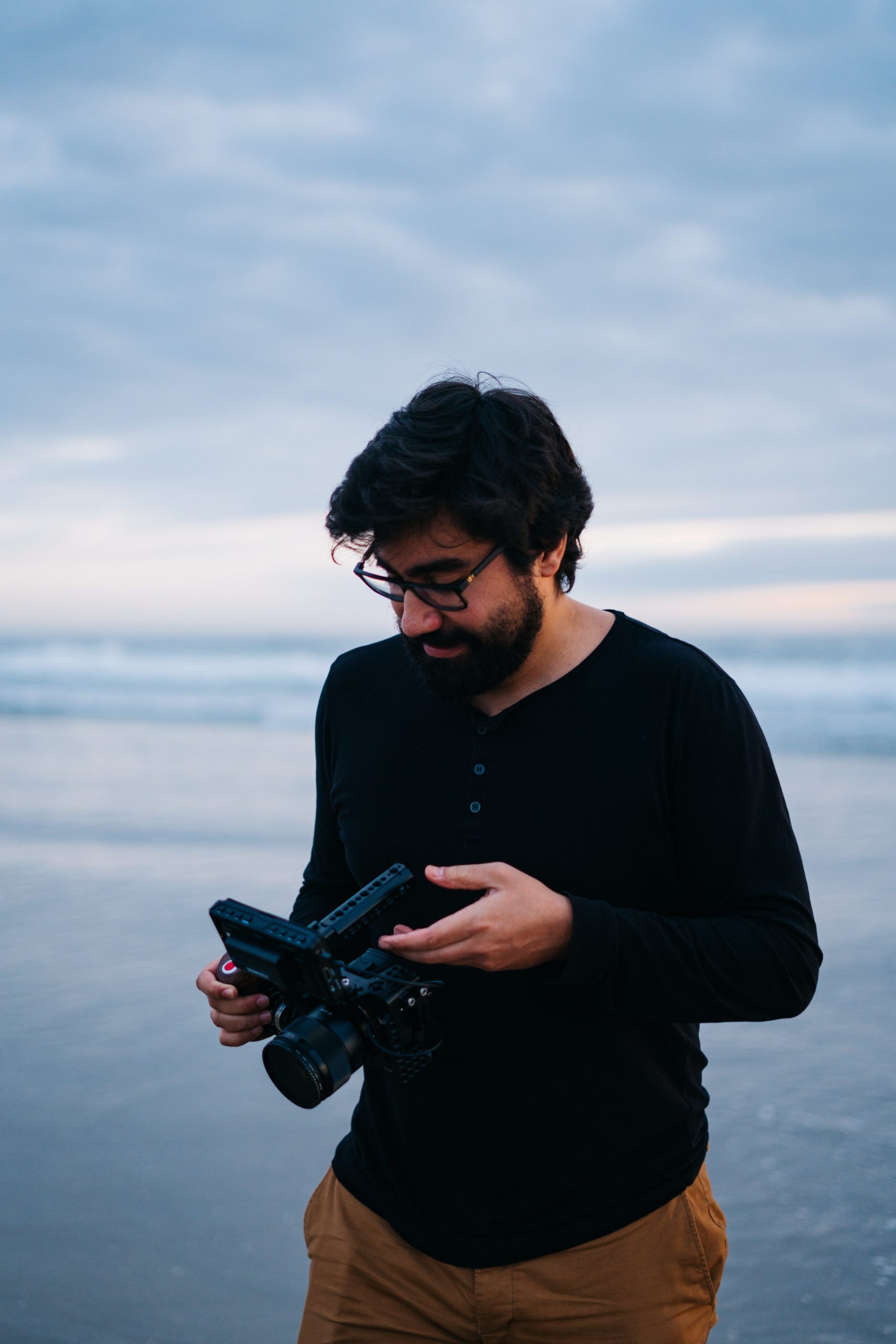 young man, holding a video camera, on the beach